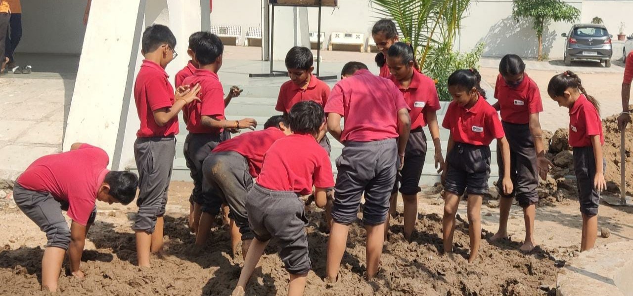Students creating mud house model at Alpha International School Ahmedabad – practical environmental learning